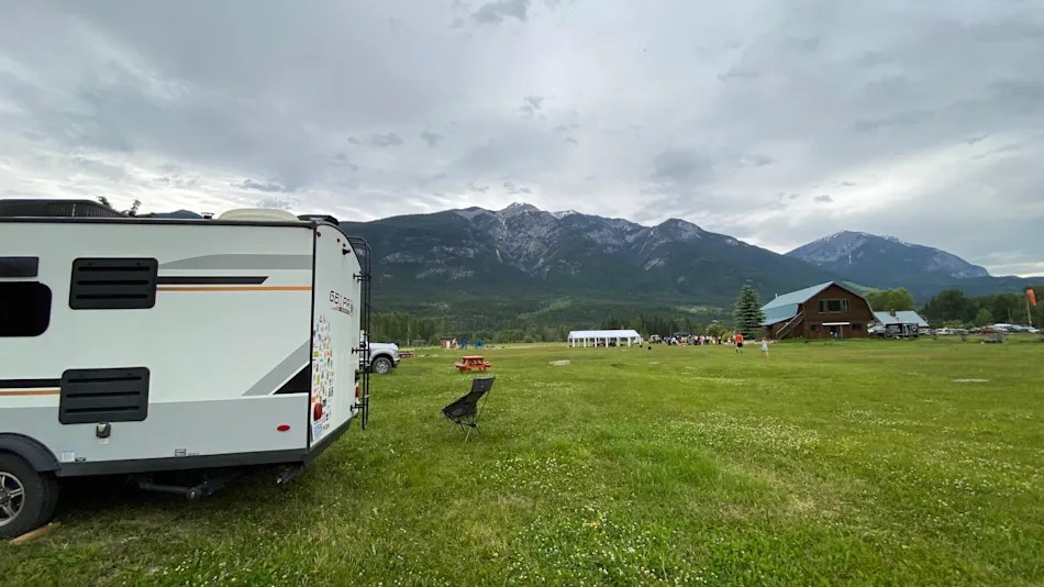 Le camping Riverfront, à Golden : une roulotte branchée sur un grand terrain gazonné, le bâtiment d’accueil et les montagnes derrière